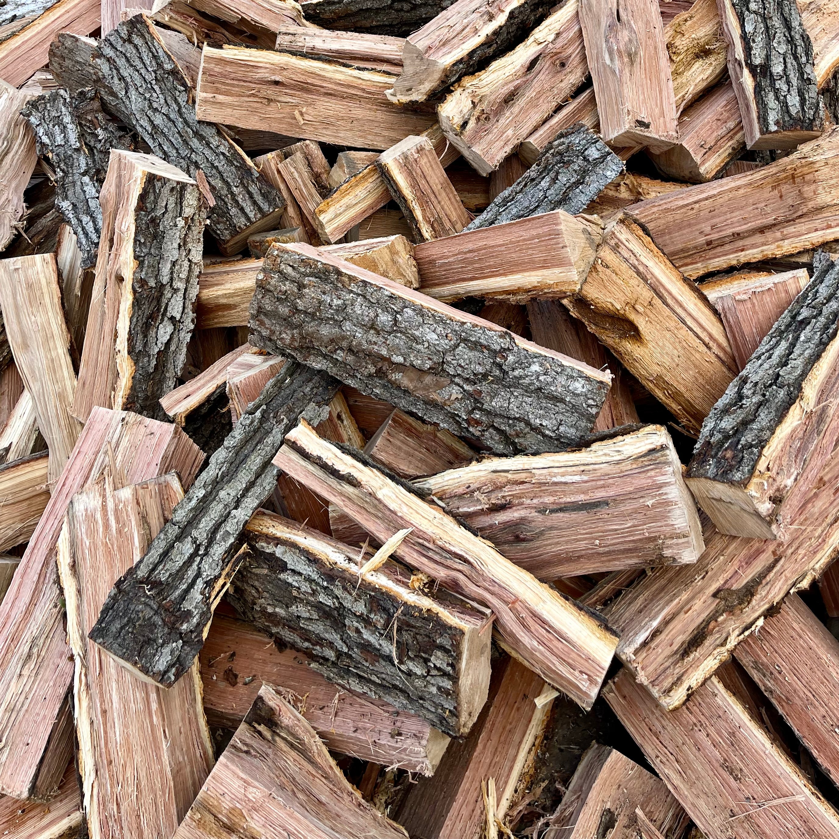 Heap of chopped wood logs with various shades of brown and gray.
