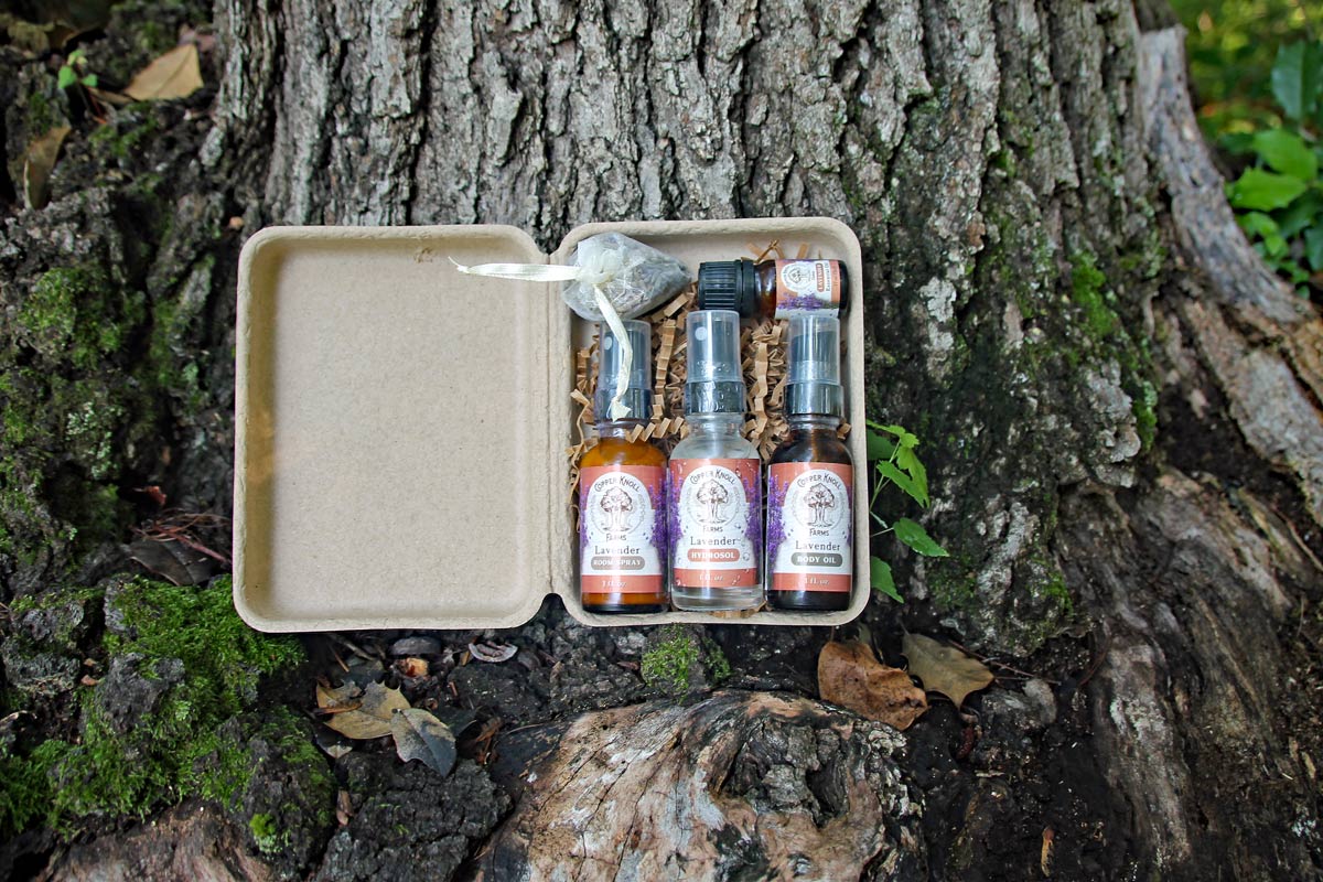 Three small bottles in a beige case on a tree trunk