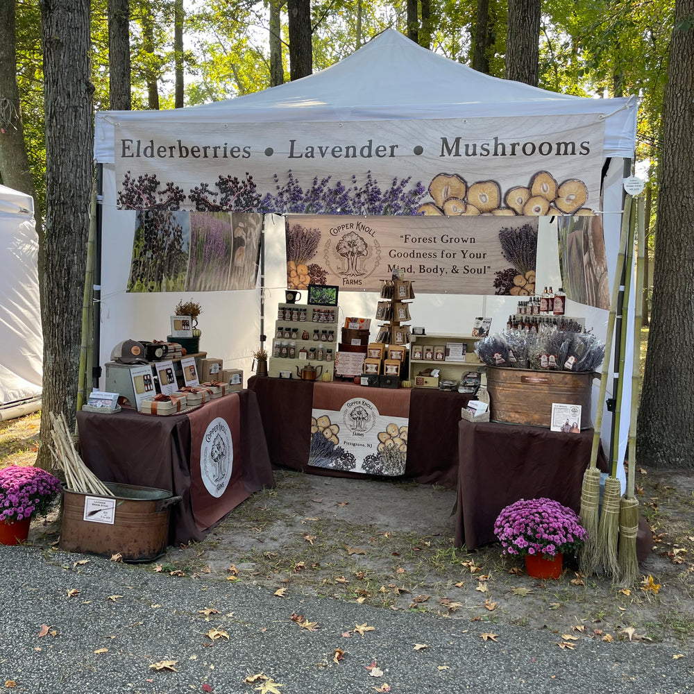 Outdoor market stall with products and branding for elderberries, lavender, and mushrooms.